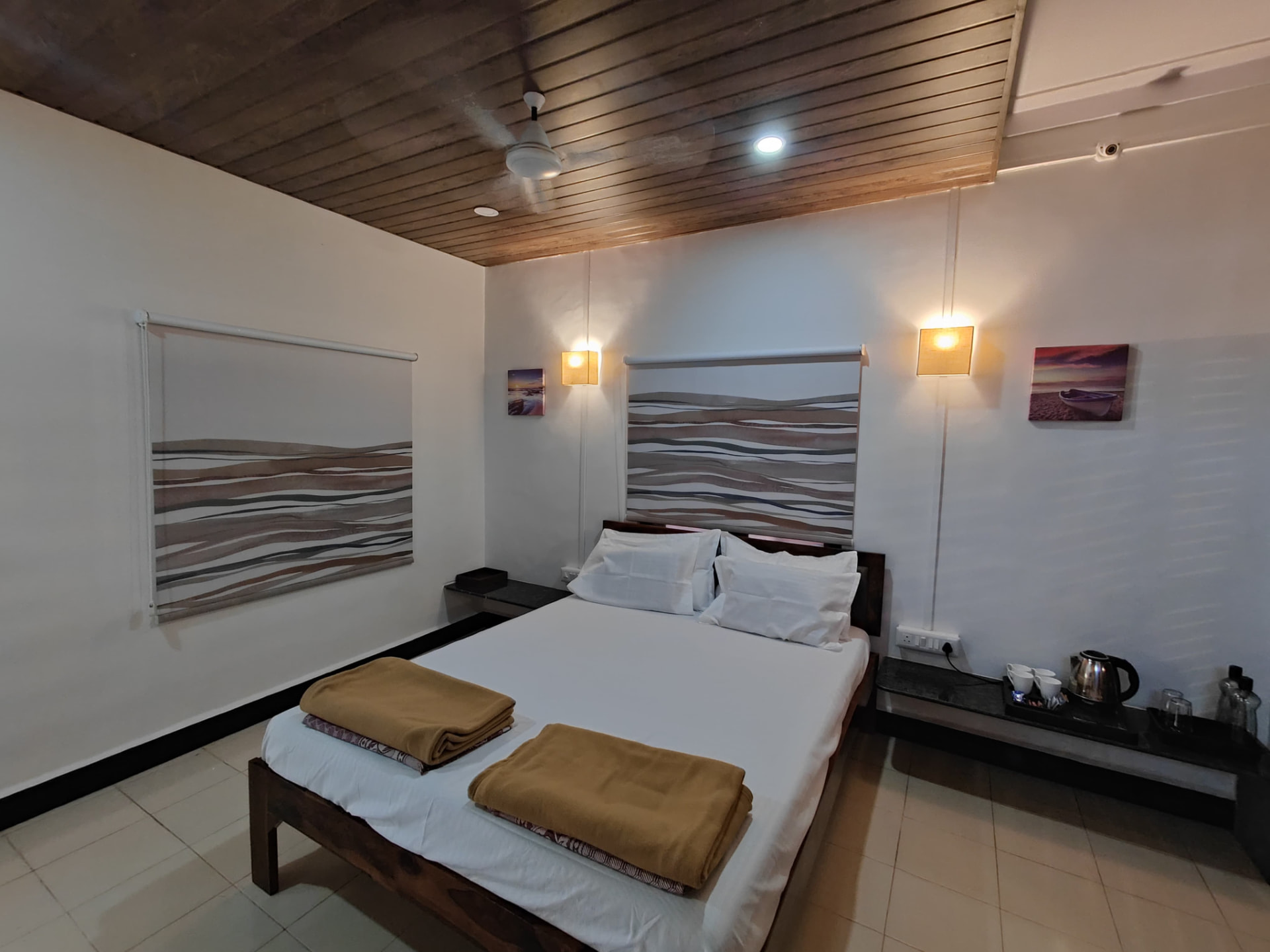 Air-conditioned bedroom with wooden ceiling and coastal artwork